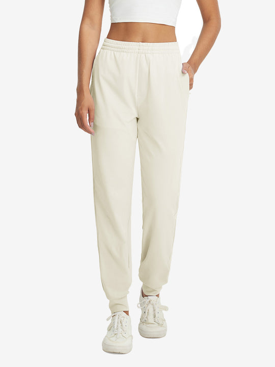 Model with hand in pocket wearing lightweight women's stretchy joggers sweatpants in cream.