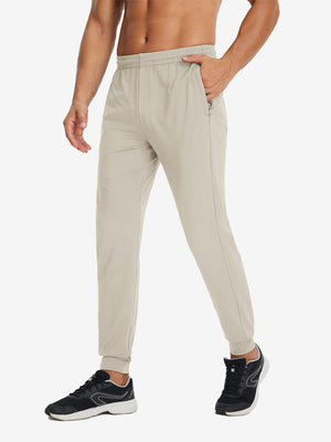 Side view of model with hand in pocket wearing lightweight traning track pants in khaki.