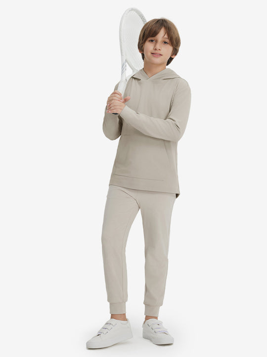 Model holding tennis racquet, wearing youth long sleeve hoodied with kangaroo pocket in khaki light, full-body.