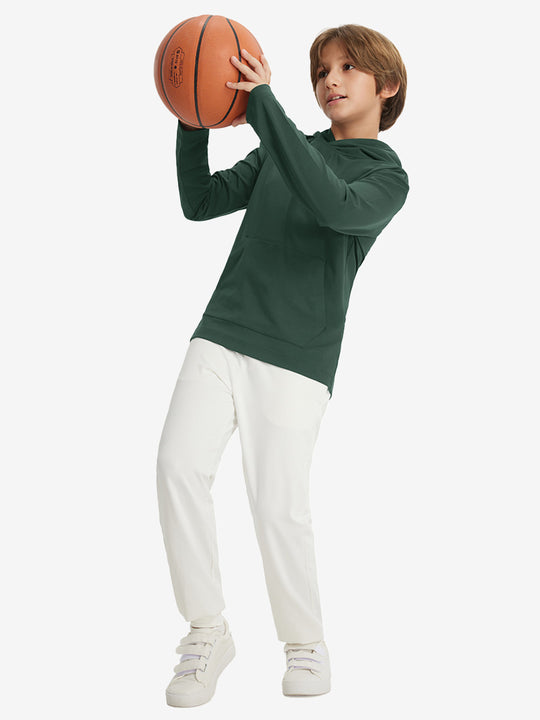 Full-body view of model holding basketball, wearing youth long sleeve hoodied with kangaroo pocket in forest green.