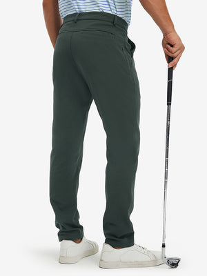 Back lower-body view of lightweight moisture wicking dress pants, model with golf club in dark green.