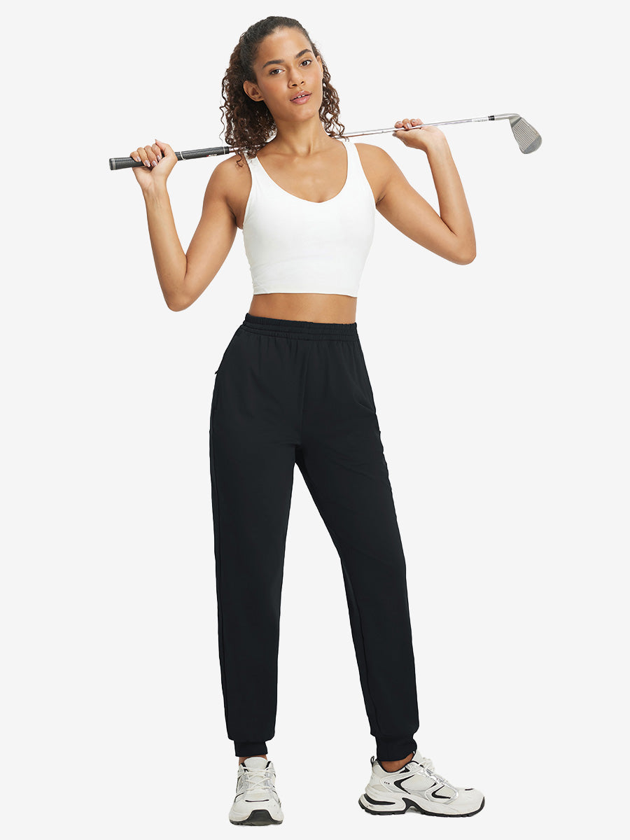 Model holding golf club behind neck while wearing lightweight women's stretchy joggers sweatpants in black.