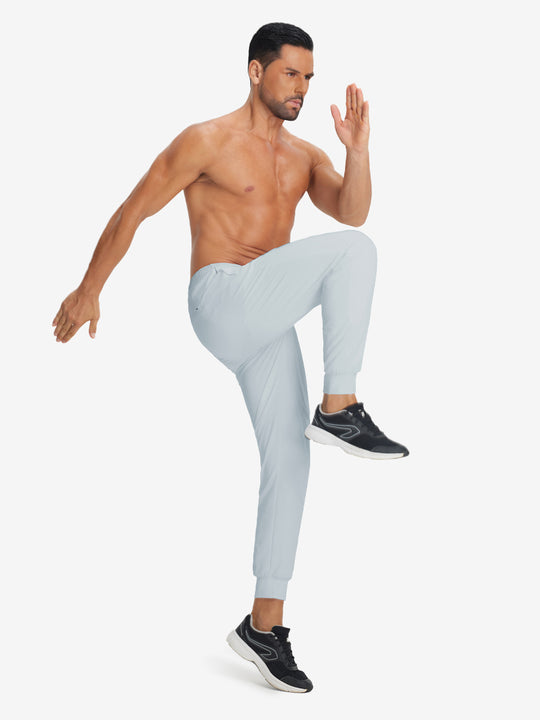 Model holding tennis racket wearing lightweight traning track pants in misty grey.