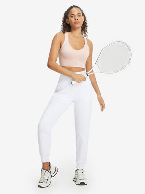 Model holding golf club behind neck while wearing lightweight women's stretchy joggers sweatpants in white.