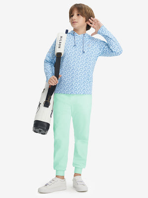 Full-body shot of model wearing turquoise fleece stretch water resistant boys joggers with a golf bag on her back.