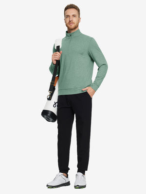 Model carrying a tennis bag, wearing dark green melange quarter zip melange pullover in full-body view.