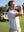 Model in white grey sea wave performance jersey print polo holding a golf club outdoors, half-body shot