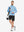 Model carrying a tennis bag, wearing light blue melange quarter zip melange pullover in full-body view.