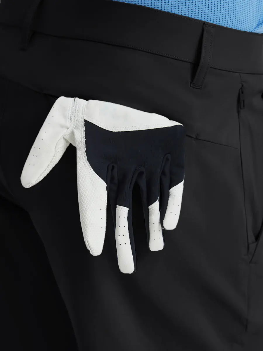 Back view of Player Fit Versatile Solid Shorts with golf glove tucked into right pocket – BLACK