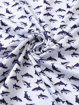 Close-up of white purple shark performance print boys golf polo fabric showing moisture-wicking texture and vibrant pattern.
