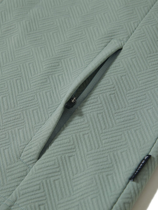 Close-up of jacket pocket showing fine stitching and insulation detail, textured insulated winter jacket, beryl green.