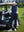 Model leaning on a golf cart, wearing navy women's lightweight slim-fit puffer vest with one hand in pocket.